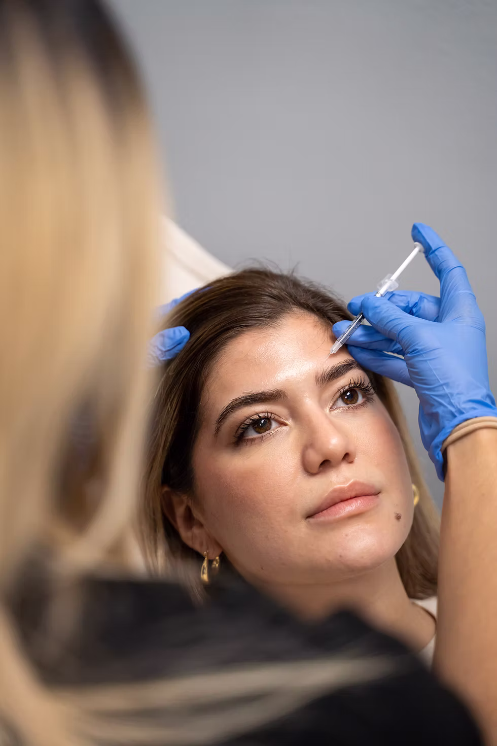 Close-up of a woman's face during a Botox procedure, with a needle near her skin